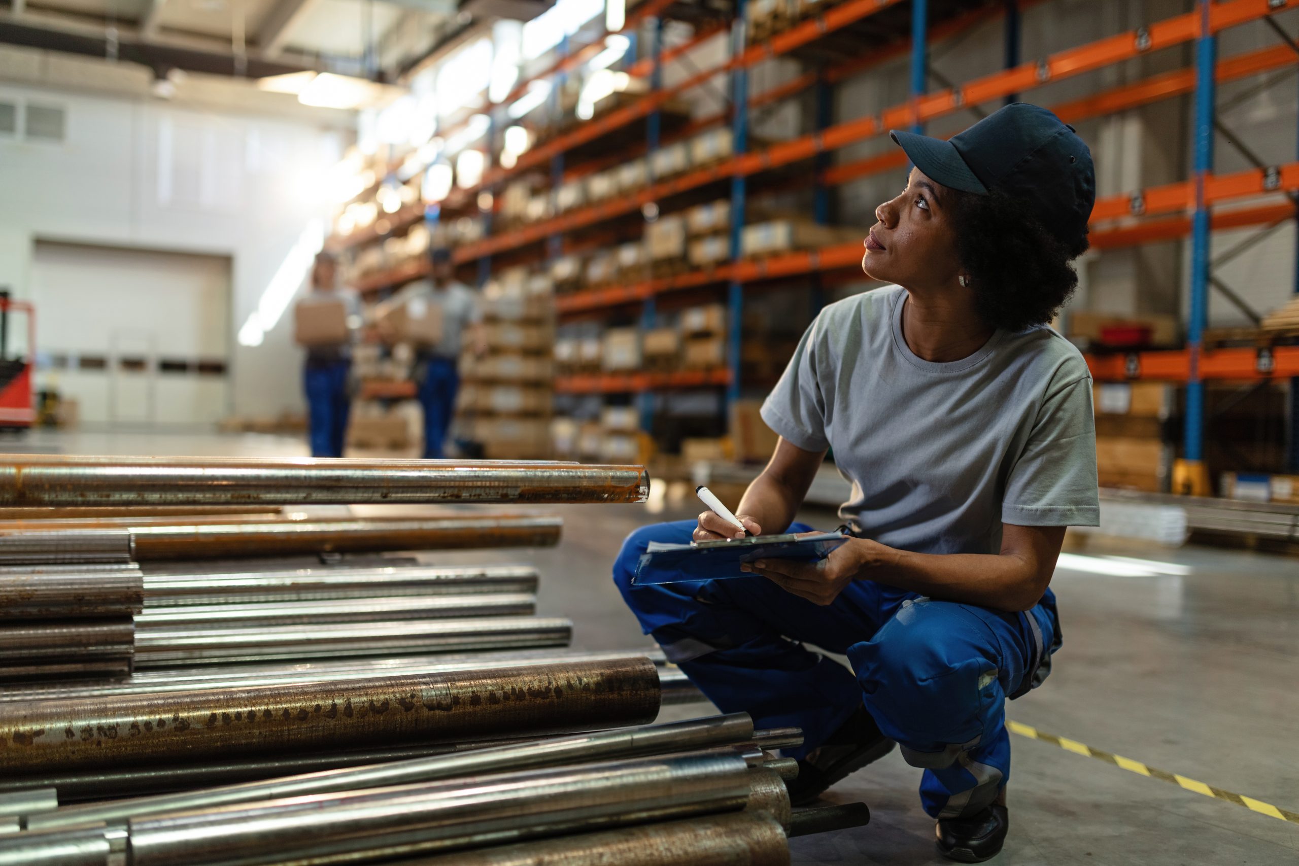 african american warehouse worker taking notes in industrial bui
